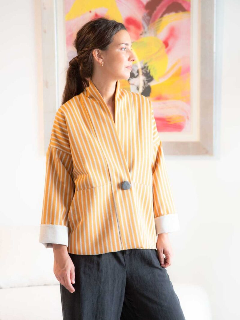 Modelo con chaqueta de inspiración kimono en sarga de espiga de algodón y lana con raya Capri, mirando hacia un lado